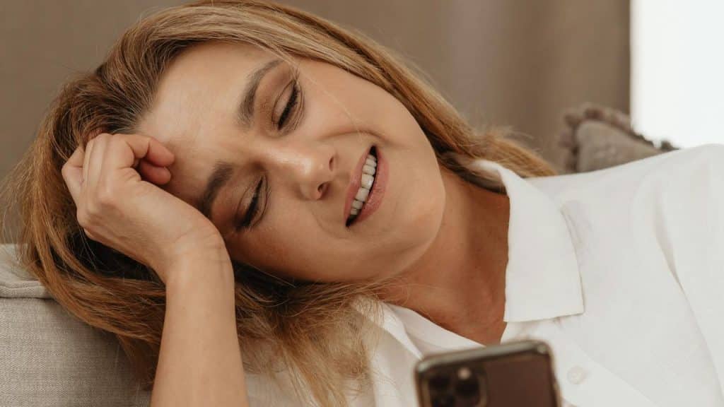 A woman smiling while looking at her phone.