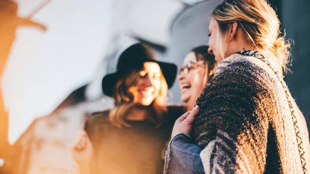 A group of friends smiling and chatting outdoors.