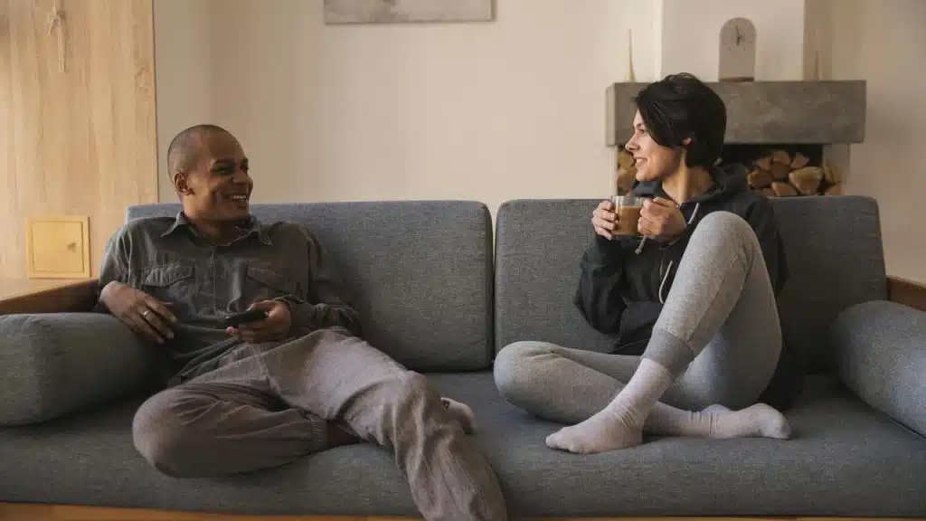 A man and woman sitting on a couch and talking.