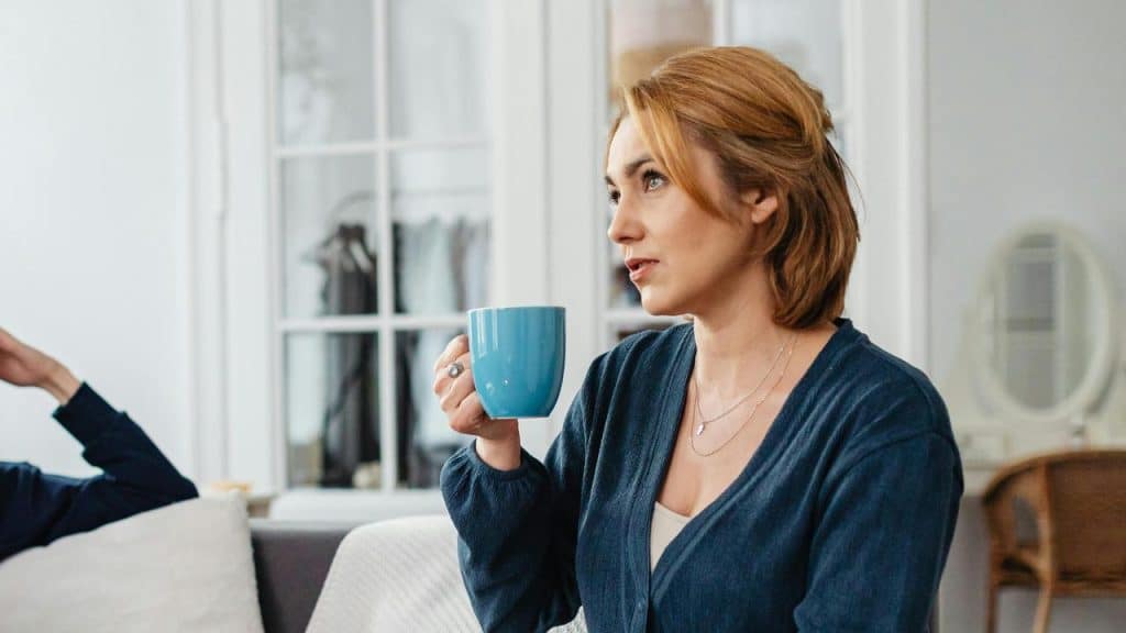 A woman holding a blue mug while sitting indoors.