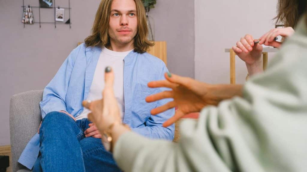 A man sitting and listening to someone speaking during a conversation.