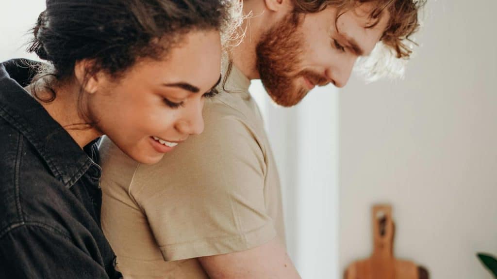 A woman hugging a man from behind in a kitchen.