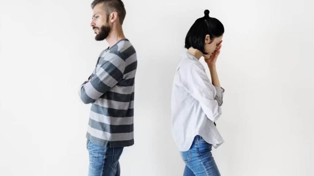 A couple standing in silence with distant expressions
