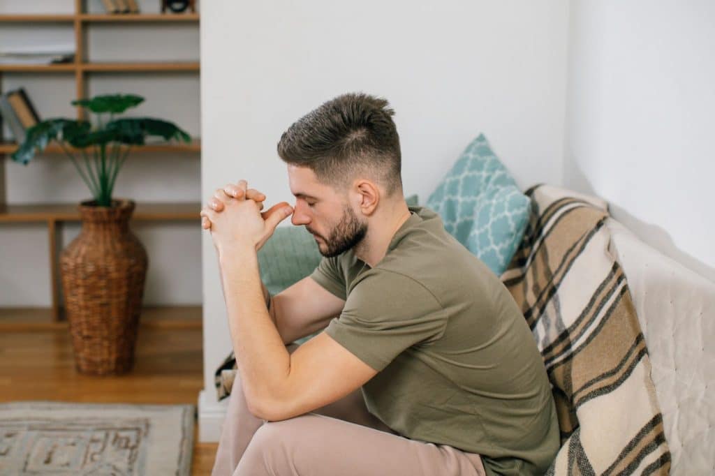 A man thinking while sitting at the sofa