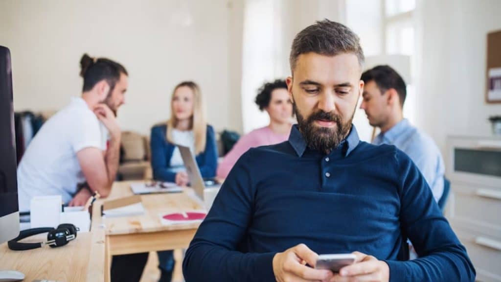 Man texting nonstop while sitting at his work desk
