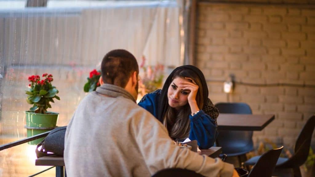 Woman looking uncomfortable as man questions her at dinner