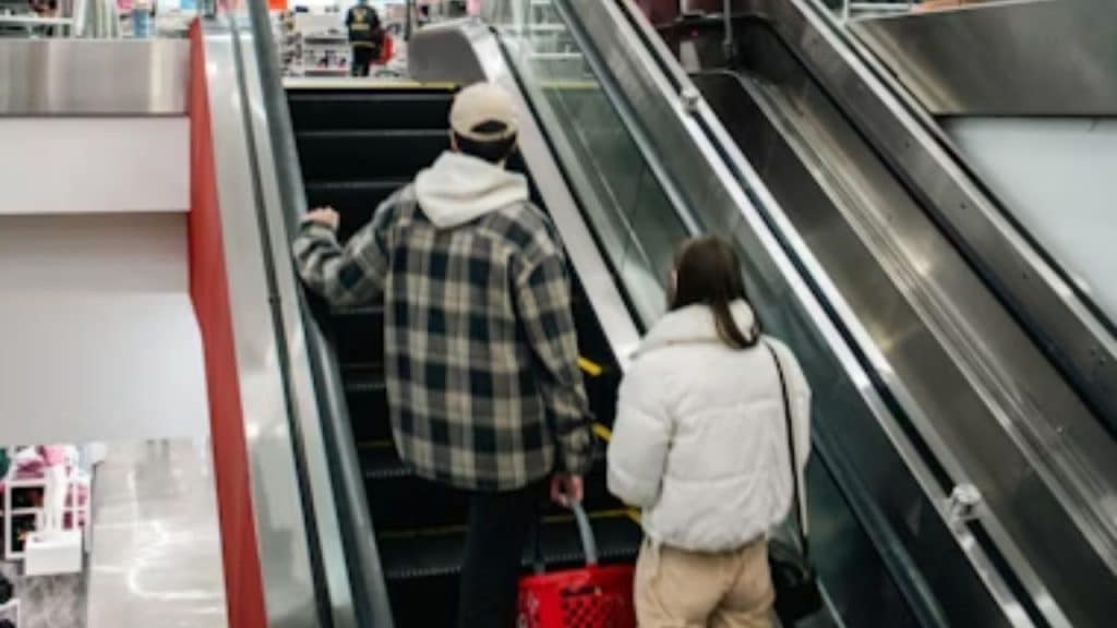 Man following the woman as she goes shopping