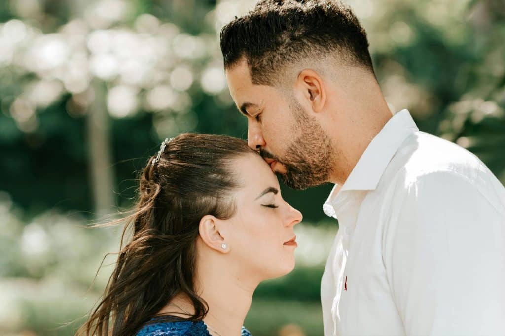 A man kissing a woman’s forehead