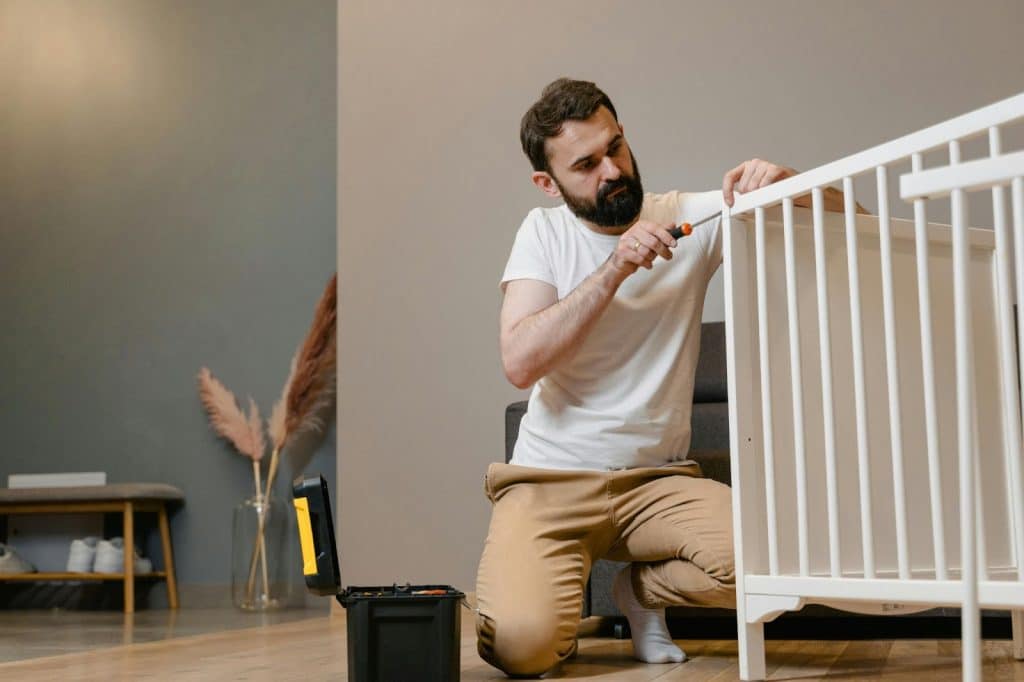 A man fixing a crib.