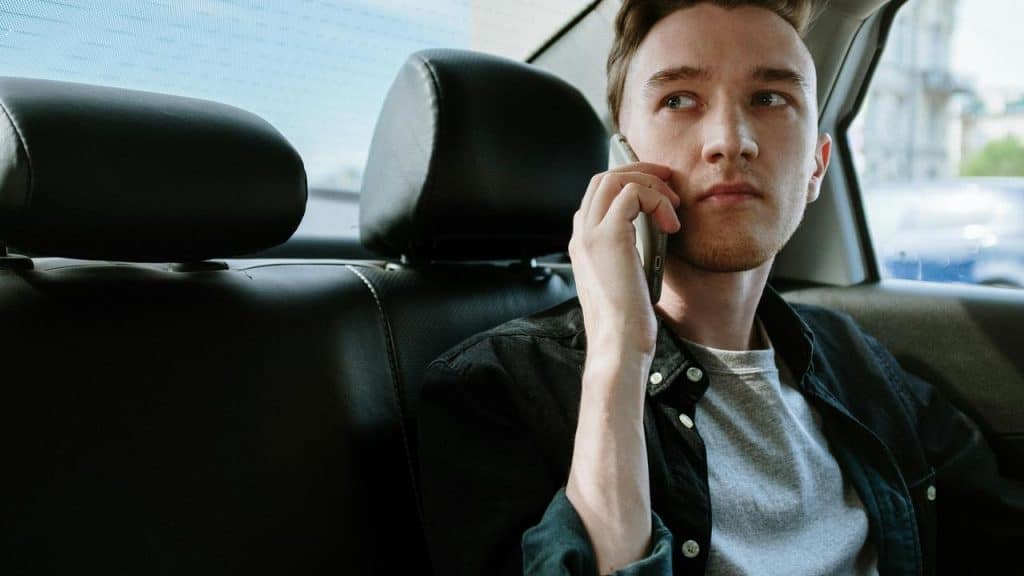 A man sitting in a car talking on the phone with a serious expression.