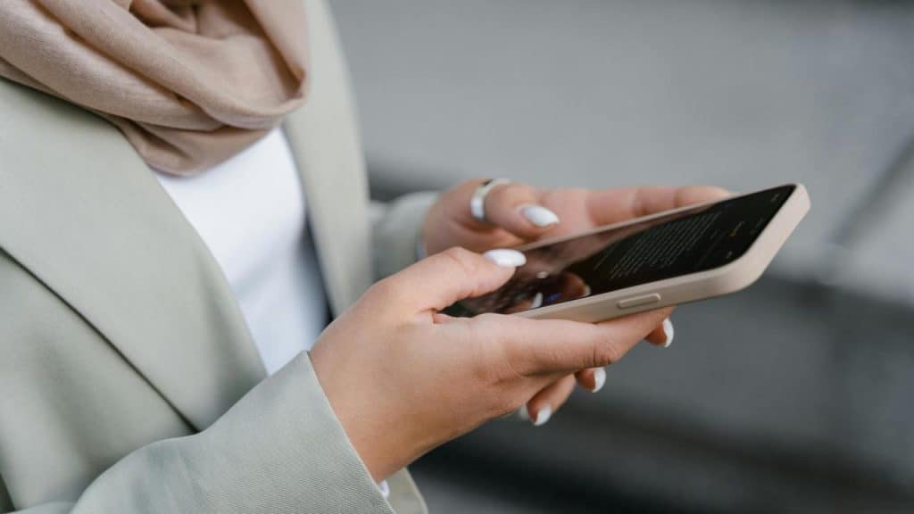A woman holding a smartphone and scrolling through the screen.