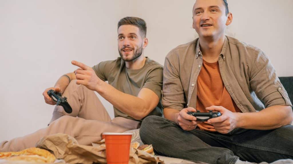 A pair of men sitting on the floor playing video games with controllers.