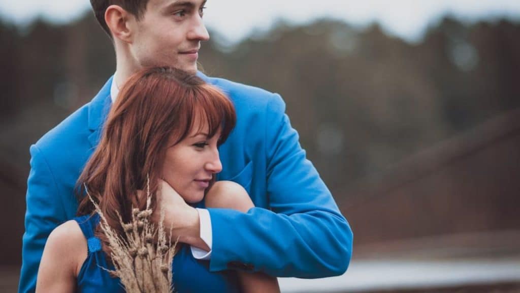 A man holding his partner tightly from behind.