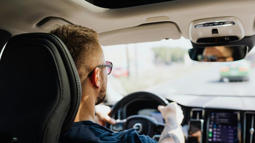 A man driving a car on a sunny day.