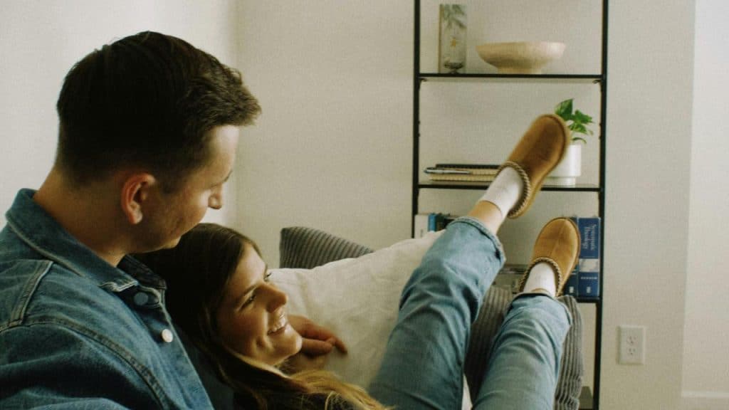 A couple relaxing on a couch and smiling at each other.