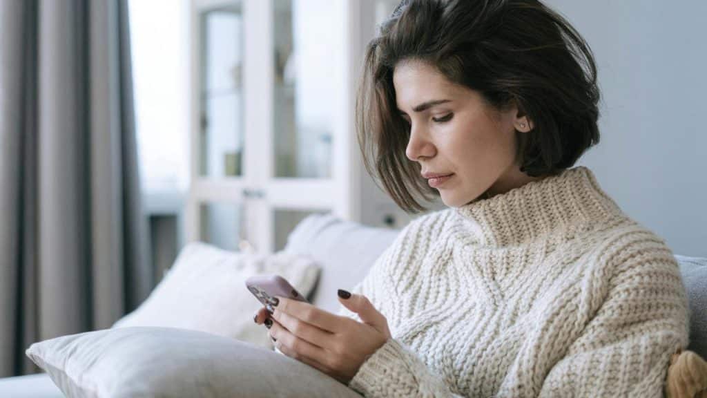 A woman sitting on a couch looking at her phone.