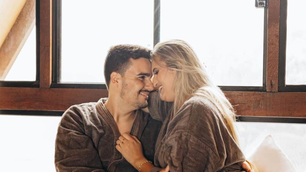 A couple sitting close together smiling and touching foreheads.