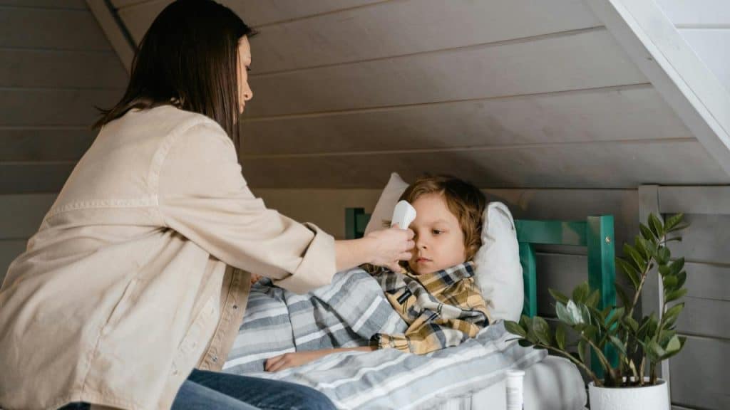 A mother checking her sick son's temperature with a thermometer.