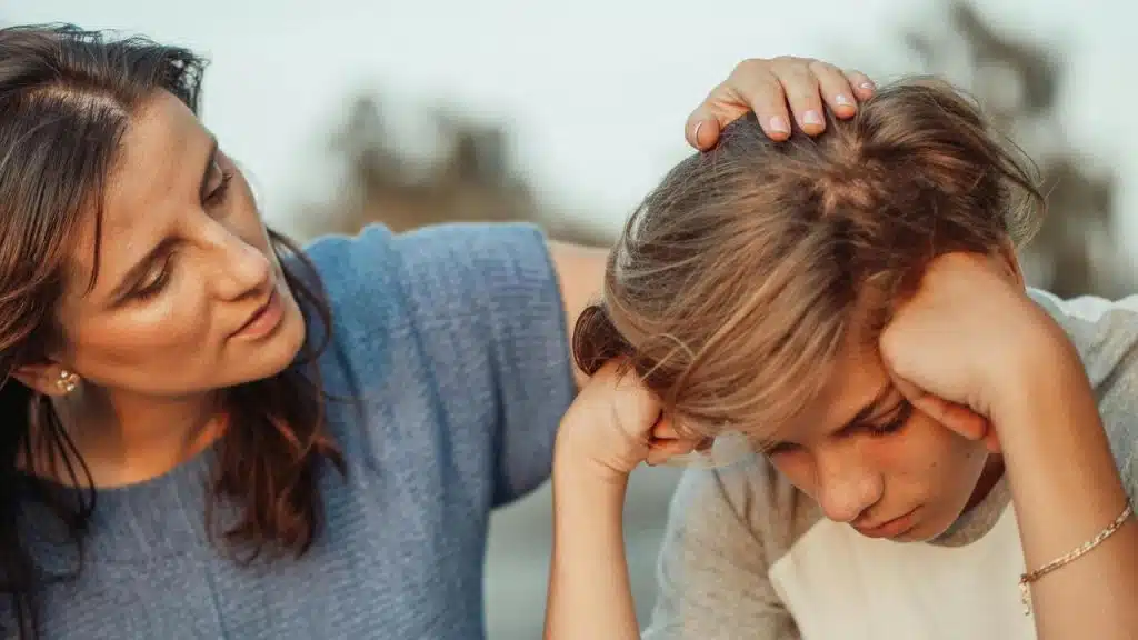 A mother comforting her upset son outdoors.