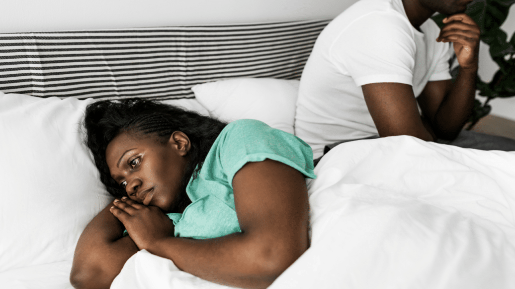 A couple not looking at each other in the bedroom