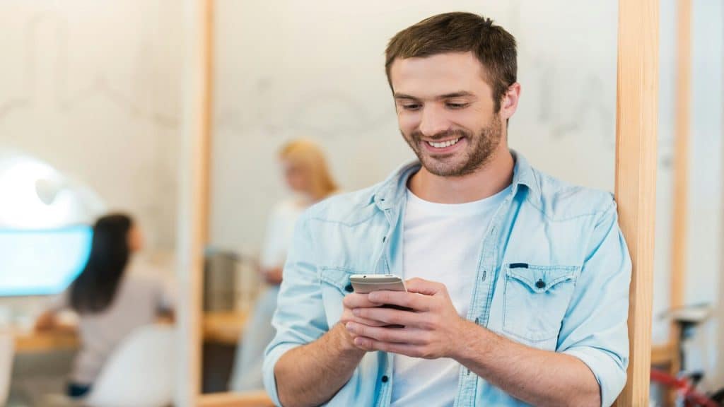 A man smiling while texting