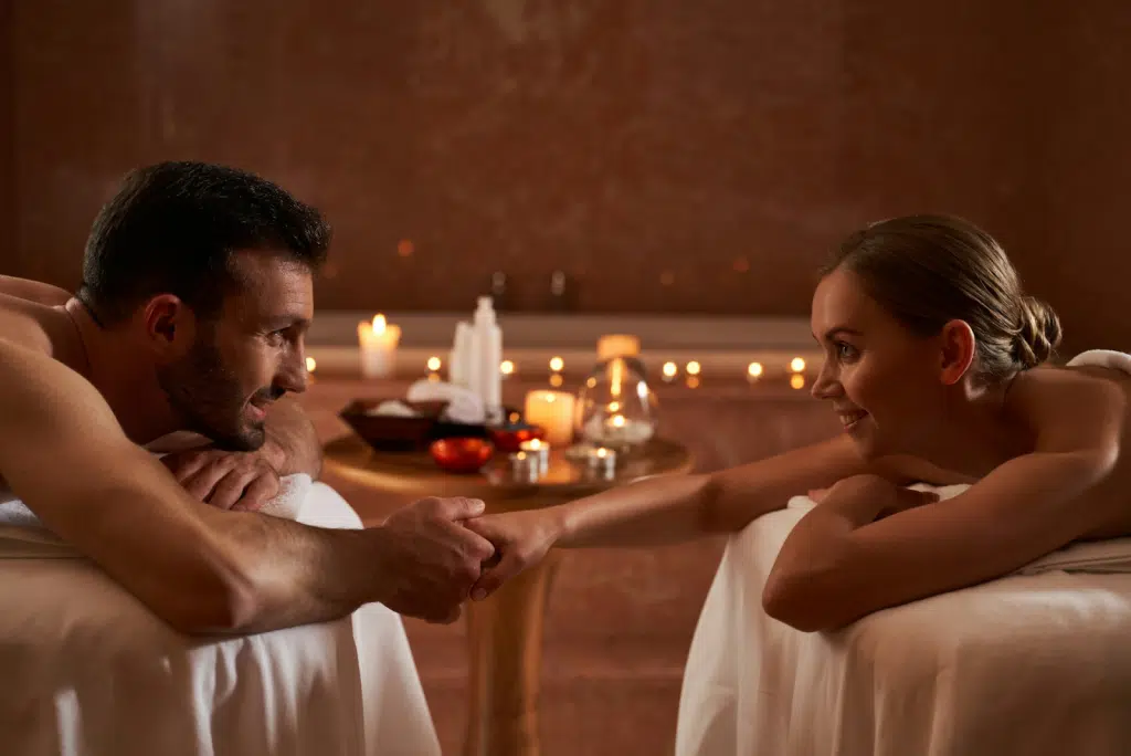 Happy young couple lying on massage tables.