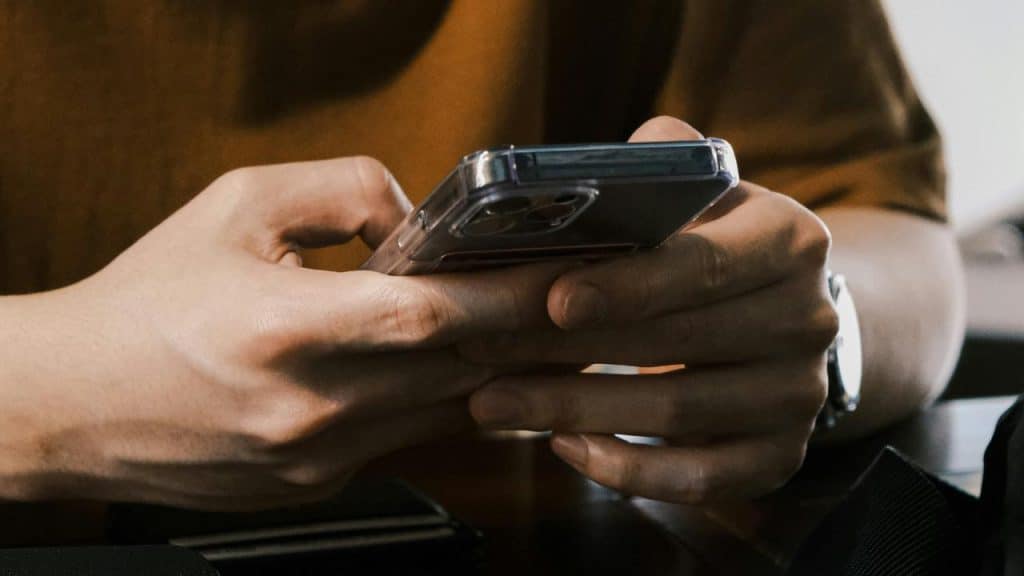 A person holding a smartphone and typing a message.