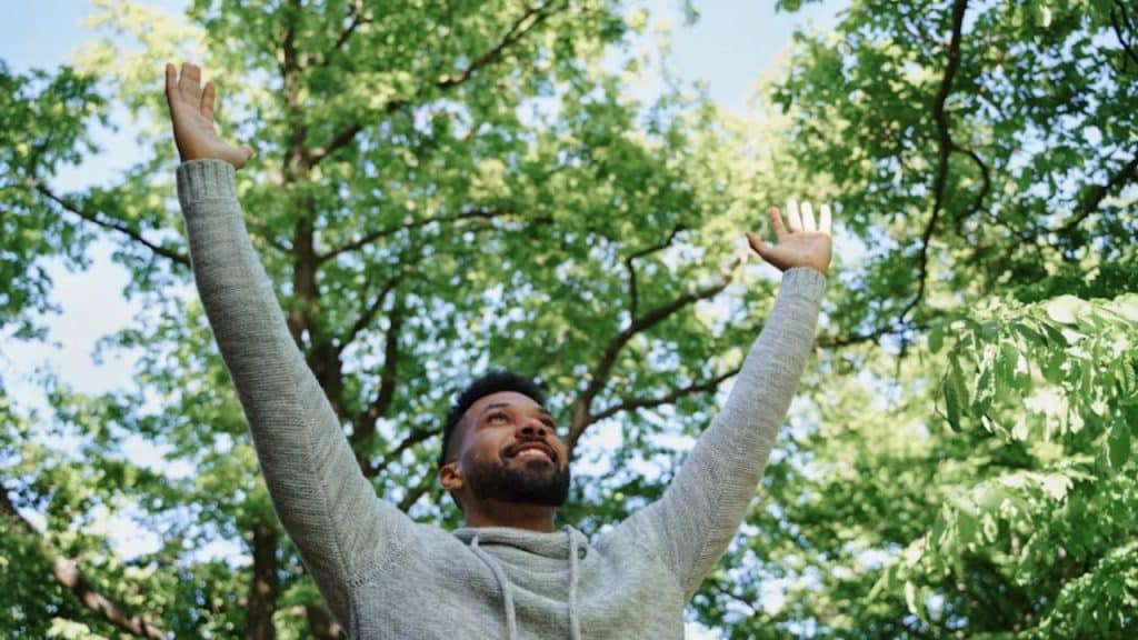 A man standing on a trail, raising both hands symbolizing new beginnings after divorce