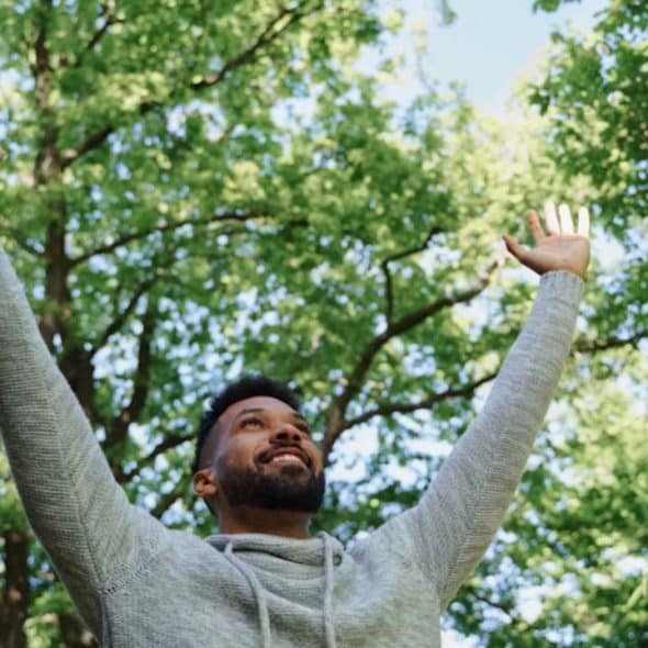 A man standing on a trail, raising both hands symbolizing new beginnings after divorce