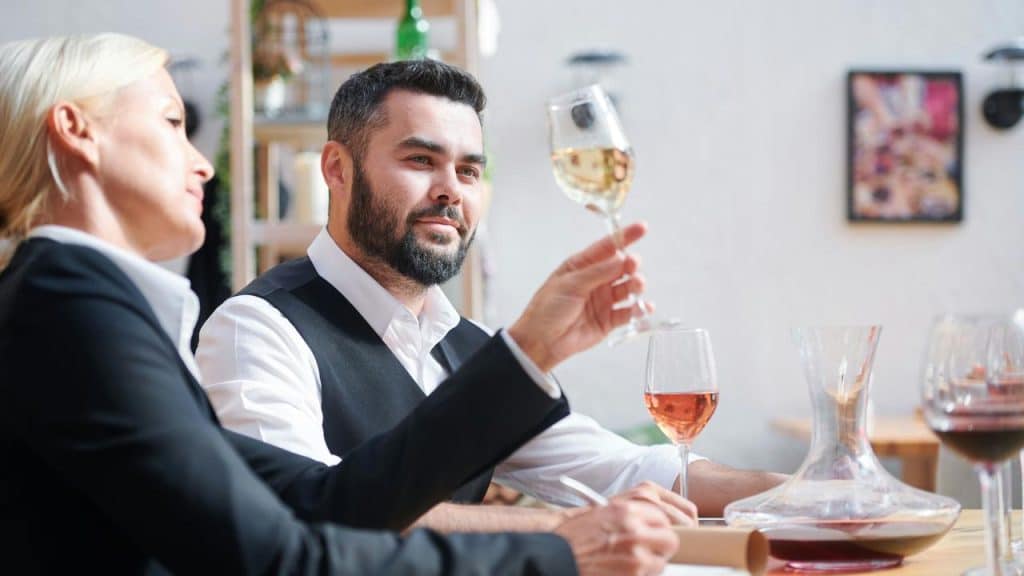 A man and woman tasting wine at a table in a bright restaurant.