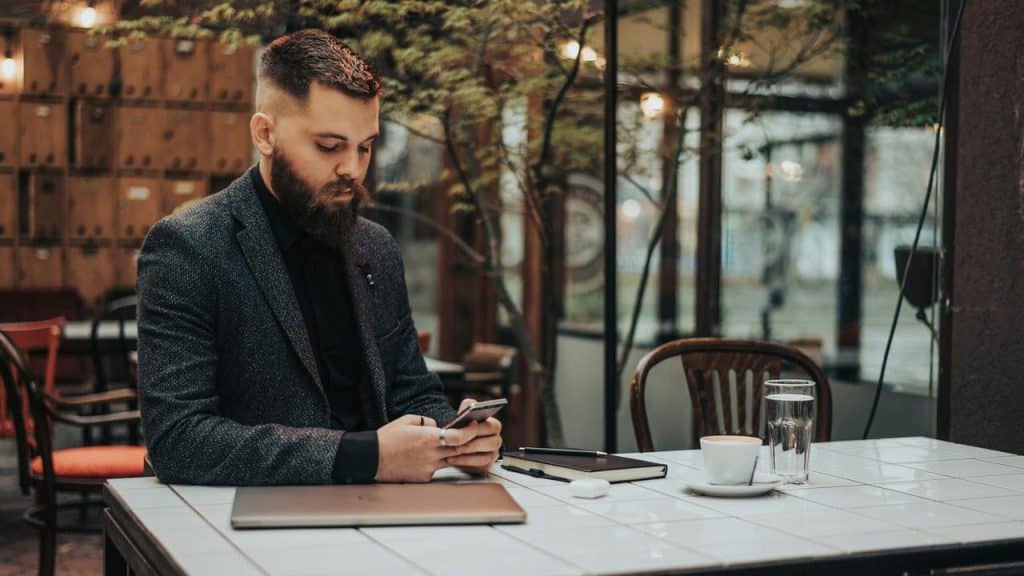 A man sitting at a café table using his smartphone.
