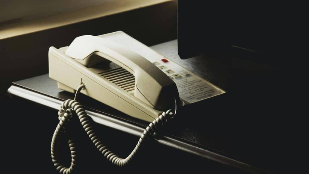 A beige corded landline phone on a dark wooden table.