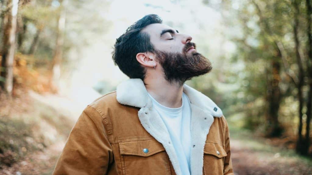 A man taking a deep breath in the woods