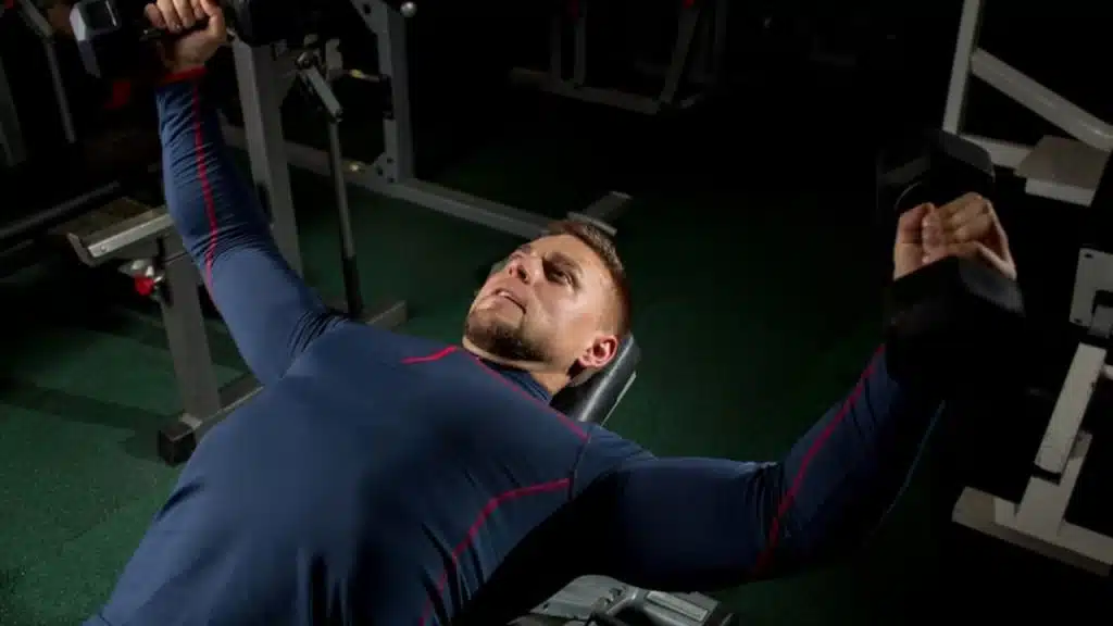 A man lifting weights at the gym with focused determination.
