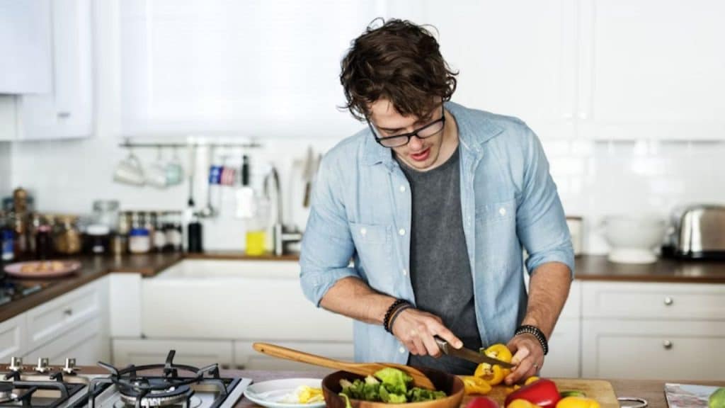 A man cooking a colorful, healthy meal in a bright kitchen