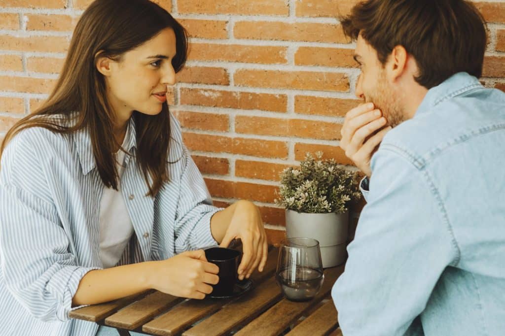 The couple is sitting at a table while talking.