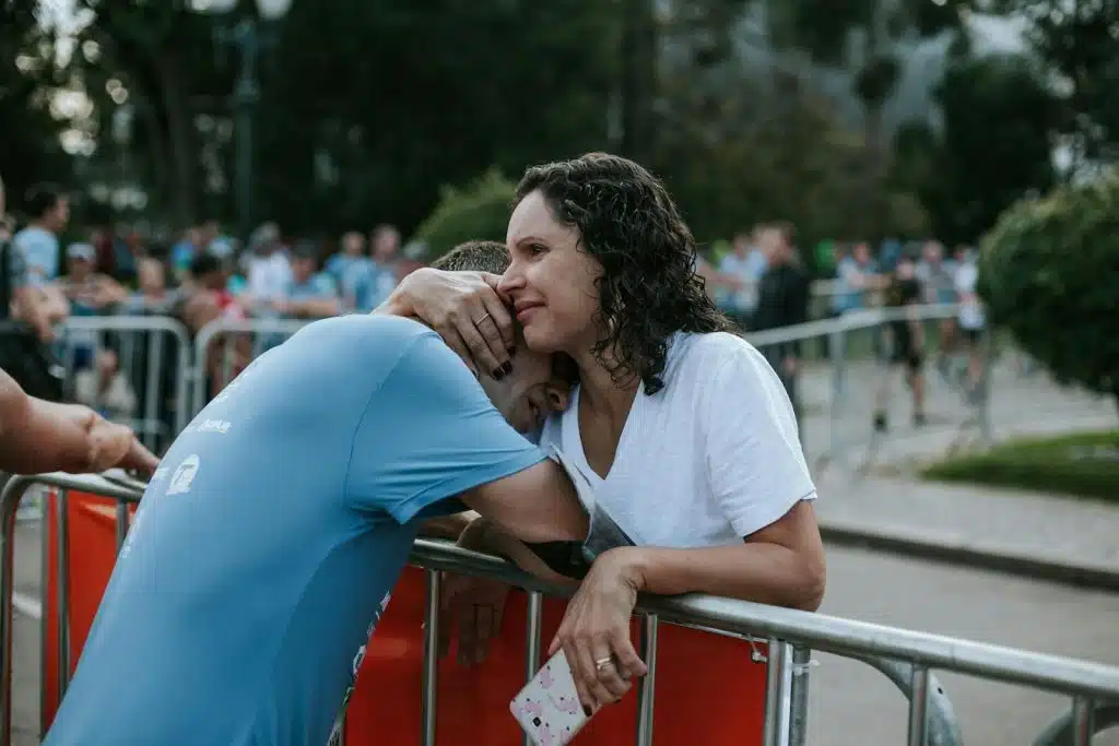 The woman is hugging the man wearing a blue shirt.