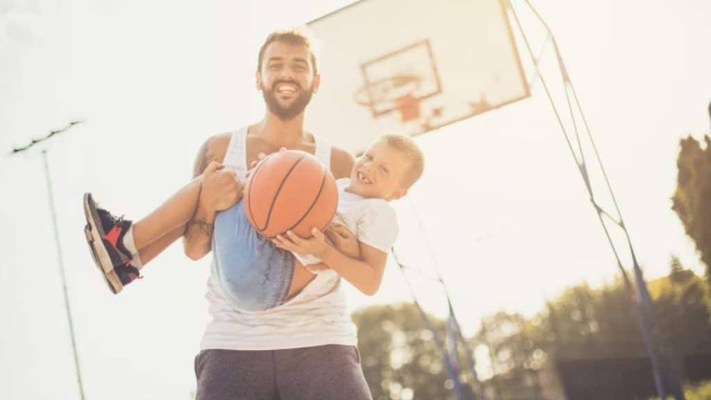 A father playing basketball with his young son outdoors