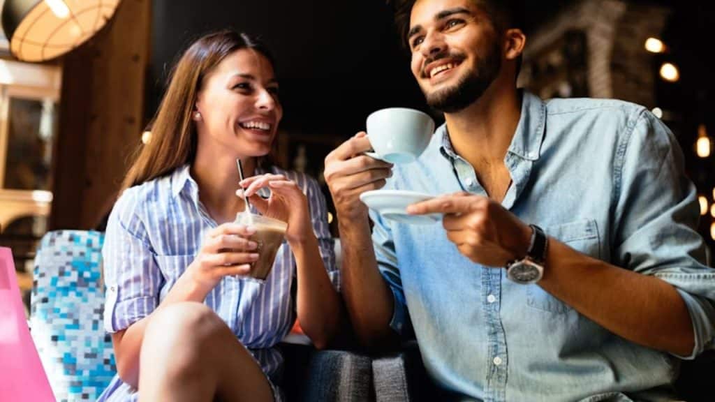 A man smiling while on a coffee date, relaxed and happy.