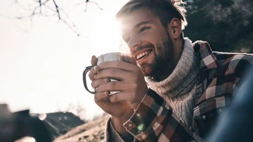 A man smiling confidently outdoors with sunlight on his face