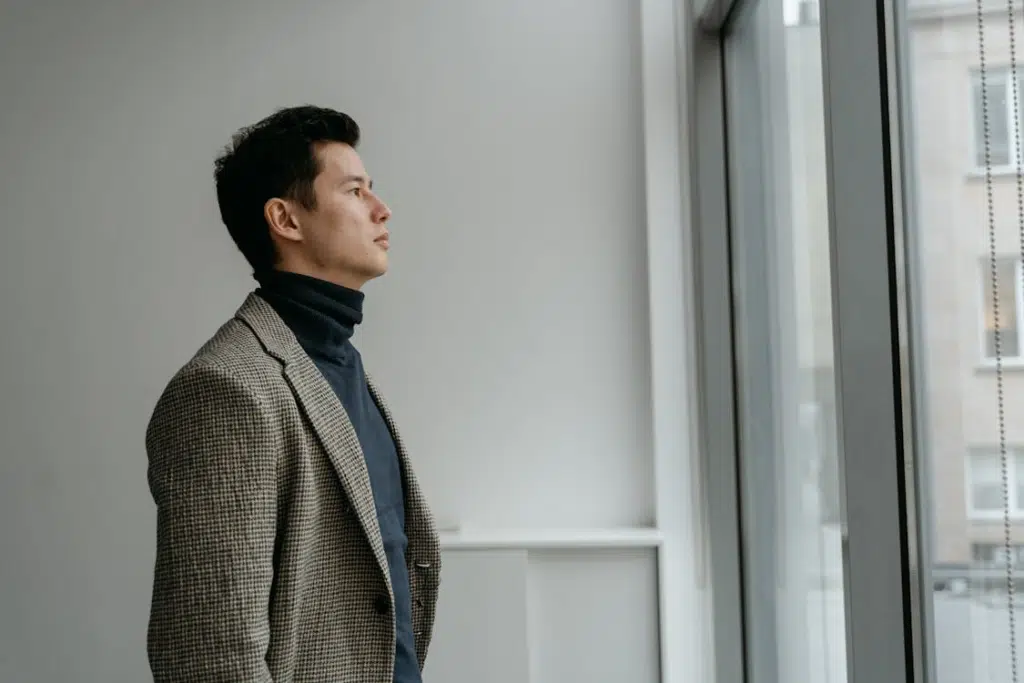A man wearing blazer looking outside the window