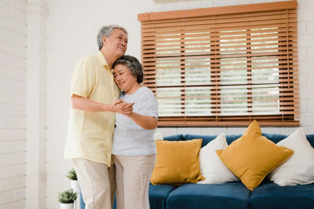 The older couple is dancing in their living room.