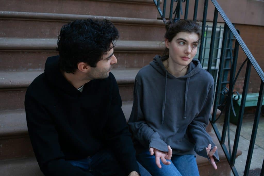The man is talking to the women while sitting on the steps.