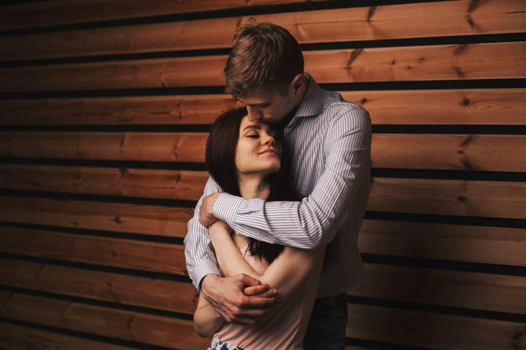 The man is hugging the smiling woman.