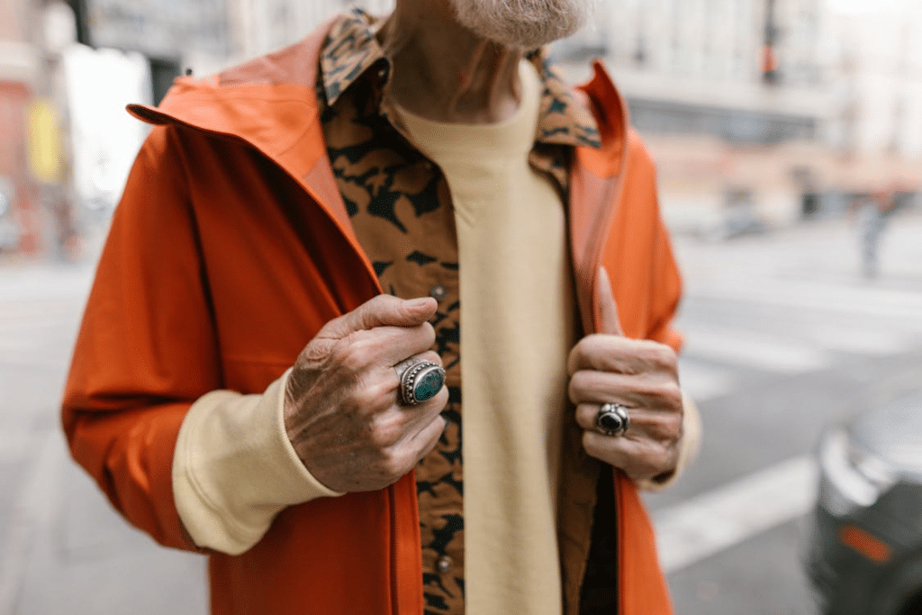 An elderly man holding an orange jacket