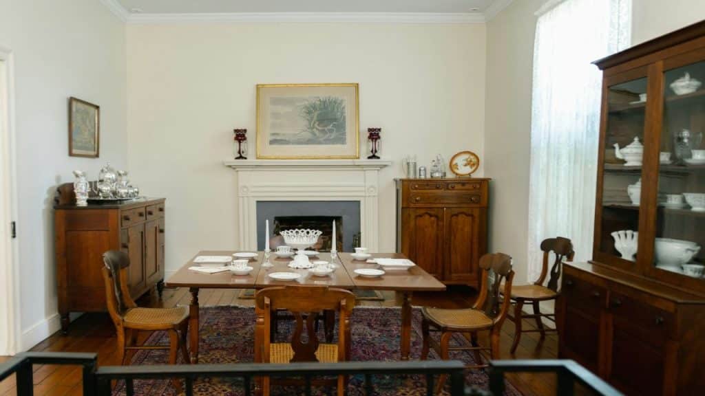 Formal dining room with a wooden table set for tea, a fireplace, and antique wooden cabinets.
