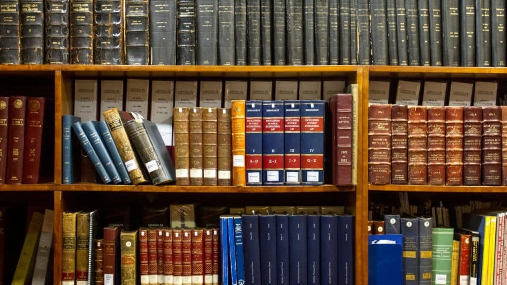 Wall-to-wall wooden bookshelves filled with hundreds of dark, leather-bound reference books and law volumes.