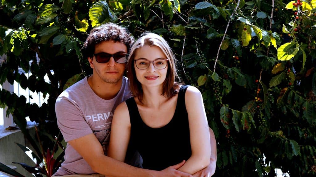 A man and a woman smiling near green plants.