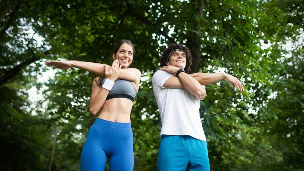 A couple stretching at the park before exercising.