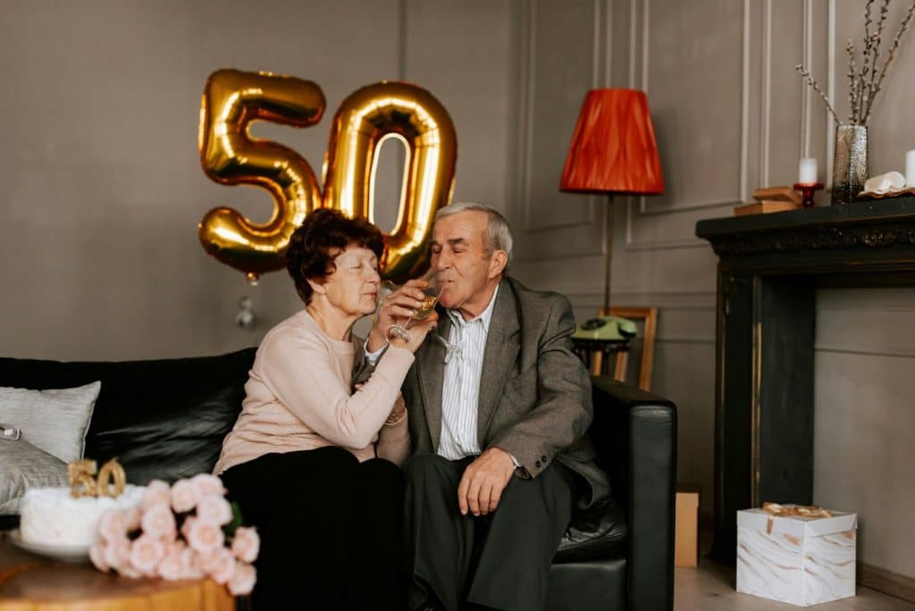 The older couple is drinking champagne, sitting beside each other.